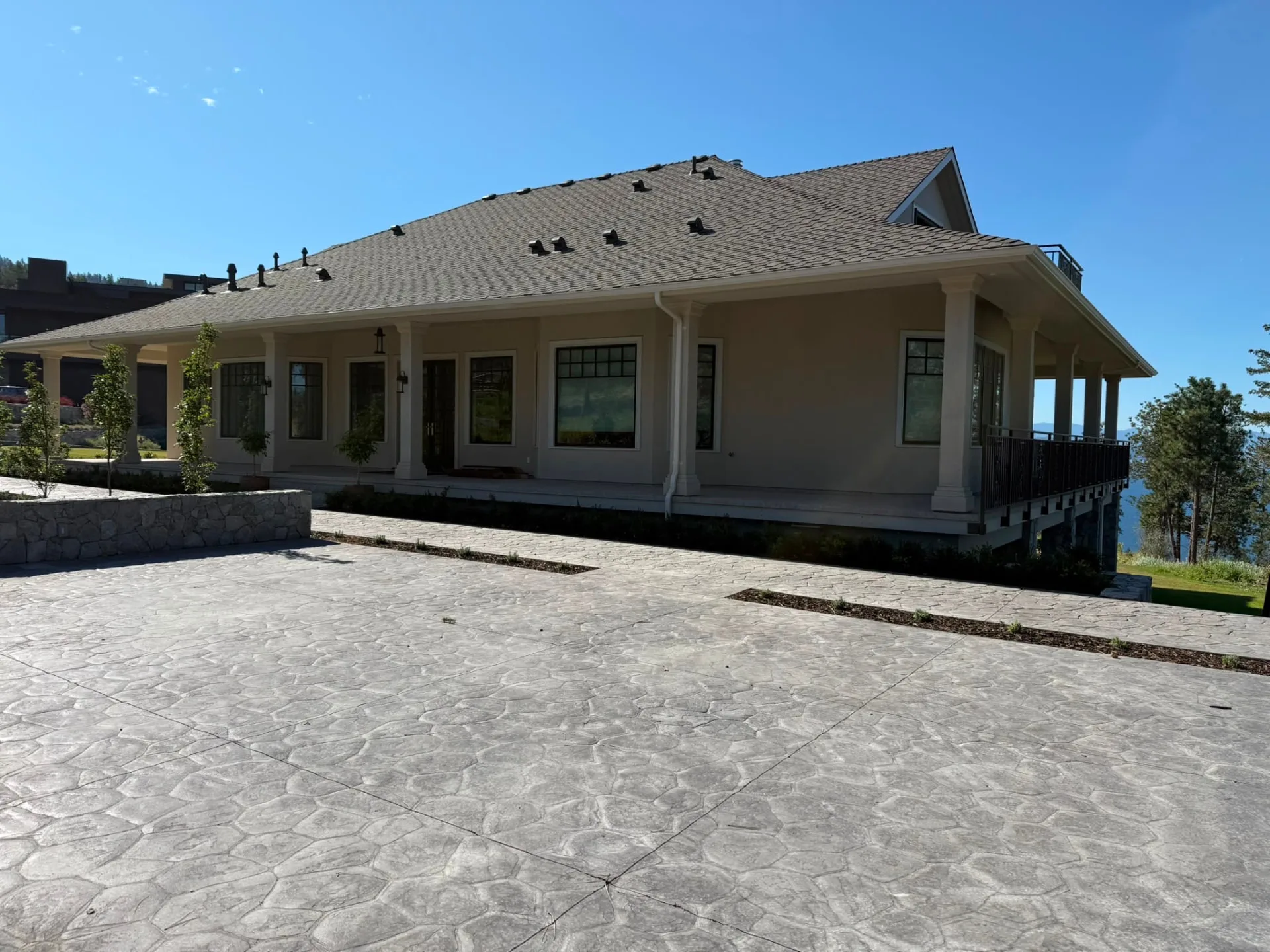 Stucco home with a wraparound porch and stamped concrete drive.